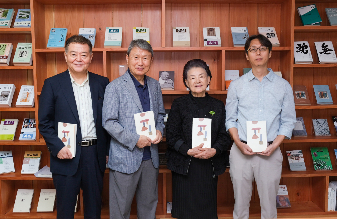 Kwon Young-min (second from left) and poet Shin Dal-ja (third from left) hold copies of Yusim in a group photo taken after a press conference in Jongno-gu, central Seoul, Aug. 29. Previous editions of Yusim are displayed on the bookshelf behind. (Manhae Musan Foundation)