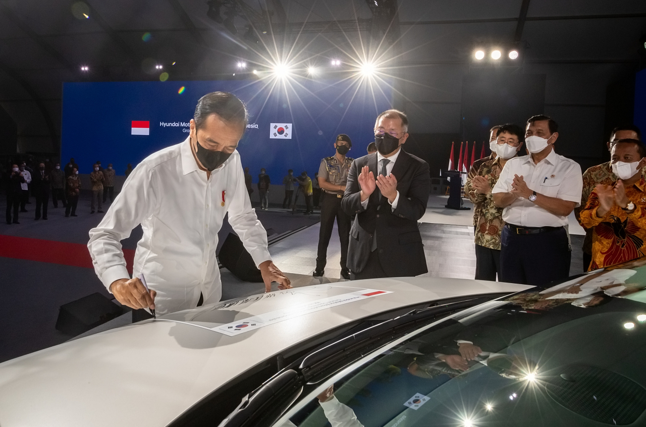 Indonesia President Joko Widodo (first from left) signs his name on Hyundai’s flagship electric vehicle Ioniq 5, while Hyundai Motor Group Executive Chair Chung Euisun (second from left) and other executives and government officials applaud during a ceremony celebrating the construction of the carmaker’s Indonesian plant in Bekasi, Indonesia, in March 2022. (Hyundai Motor Group)