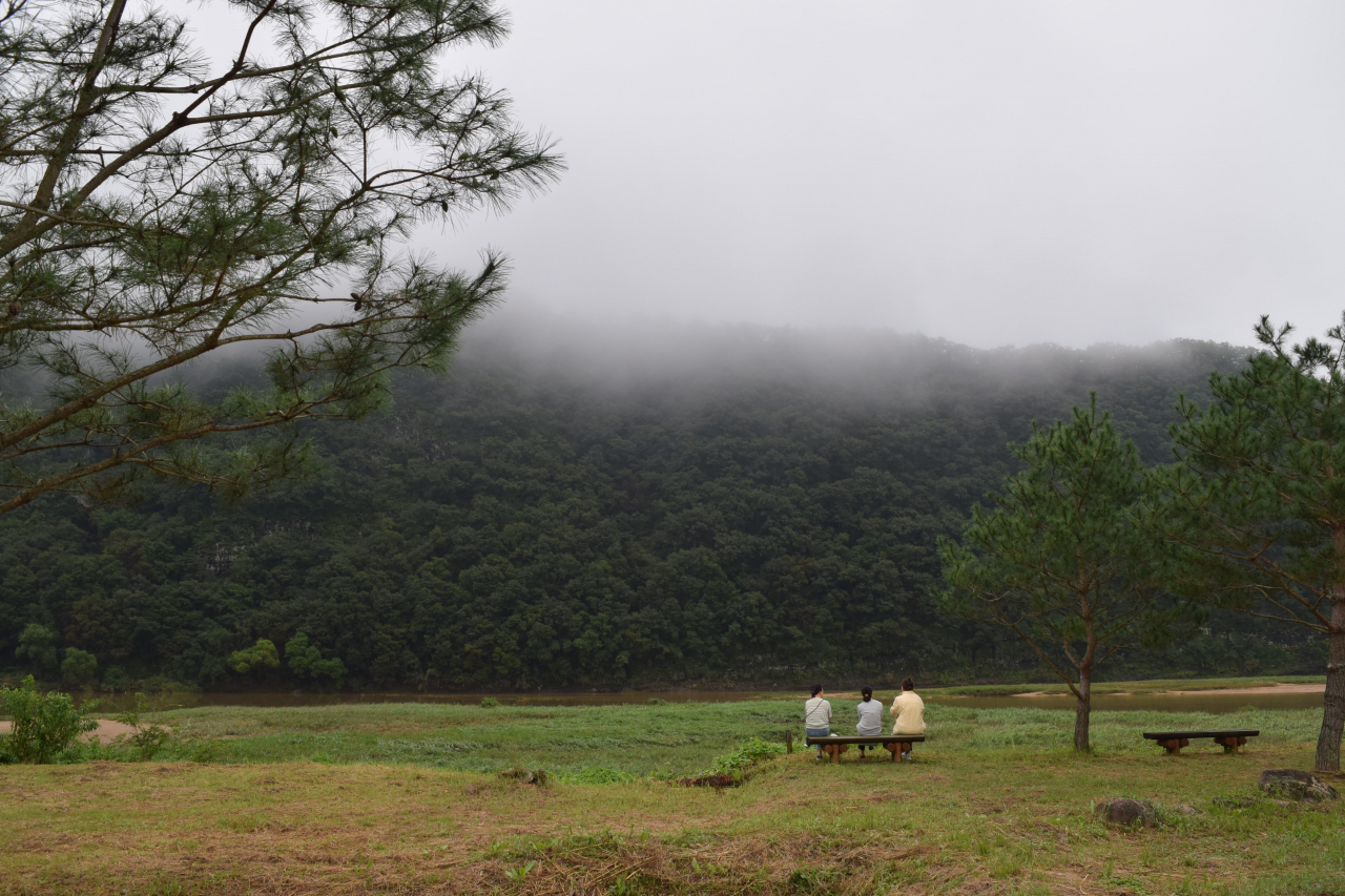 People rest on benches facing Byeongsan. (Kim Hae-yeon/ The Korea Herald)