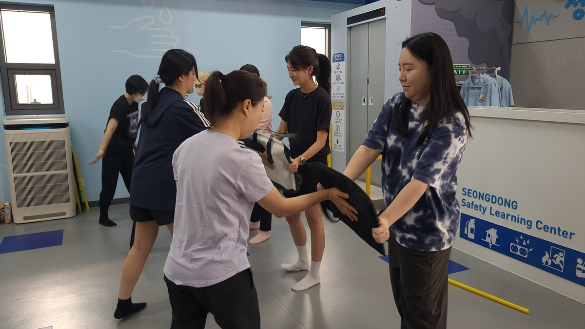 Students practice how to defend themselves from an attack using a bag during a self-defense class on Saturday. (Yonhap)