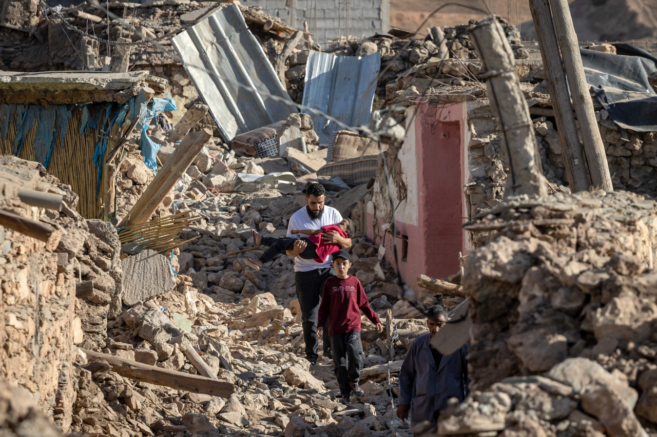 People walk past destroyed houses after an earthquake in the mountain village of Tafeghaghte, southwest of the city of Marrakesh, on Saturday. (AFP)