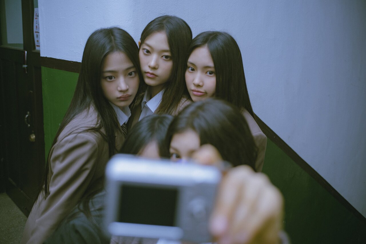 K-pop girl group NewJeans take a photo with a digital camera that was popular in the 2000s in a promotional image for the band’s single “Ditto.” (Ador)