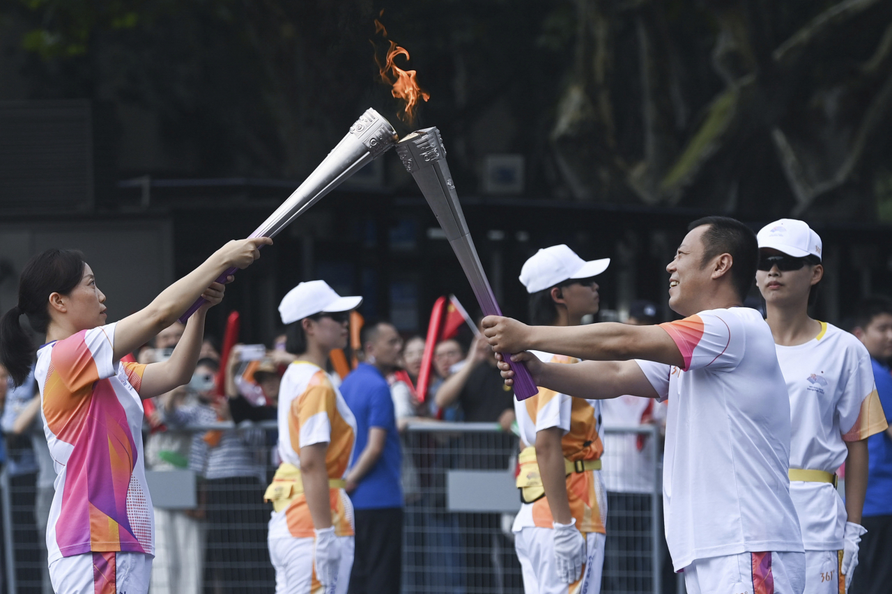 In this photo released by Xinhua News Agency, Torchbearers Zhang Tao at right and Cao Chen pass the flame during the torch relay of the 19th Asian Games in Hangzhou, capital of east China's Zhejiang Province on Sept. 8, 2023. (Photo - AP)