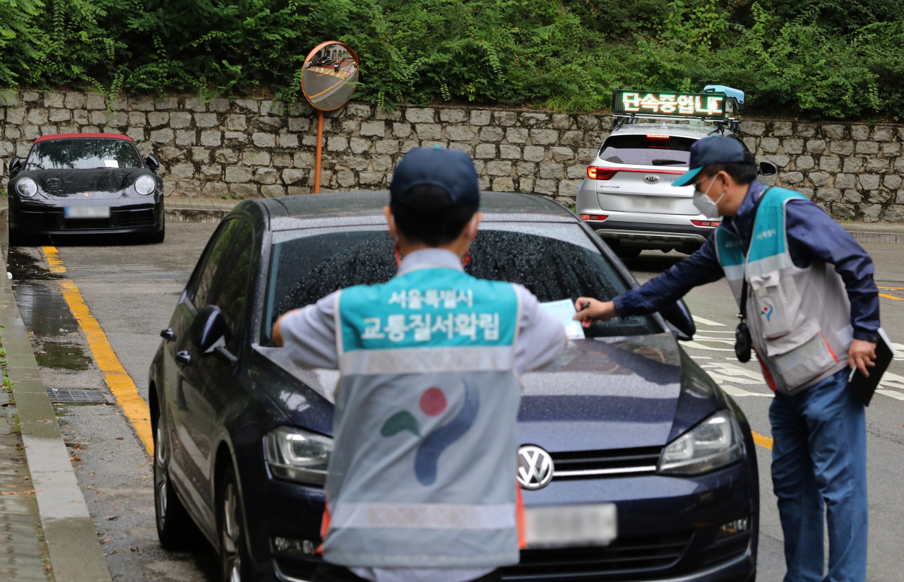 Public officials issue a ticket to an illegally parked car in a school zone in Seoul, Aug. 29, 2022. (Newsis)