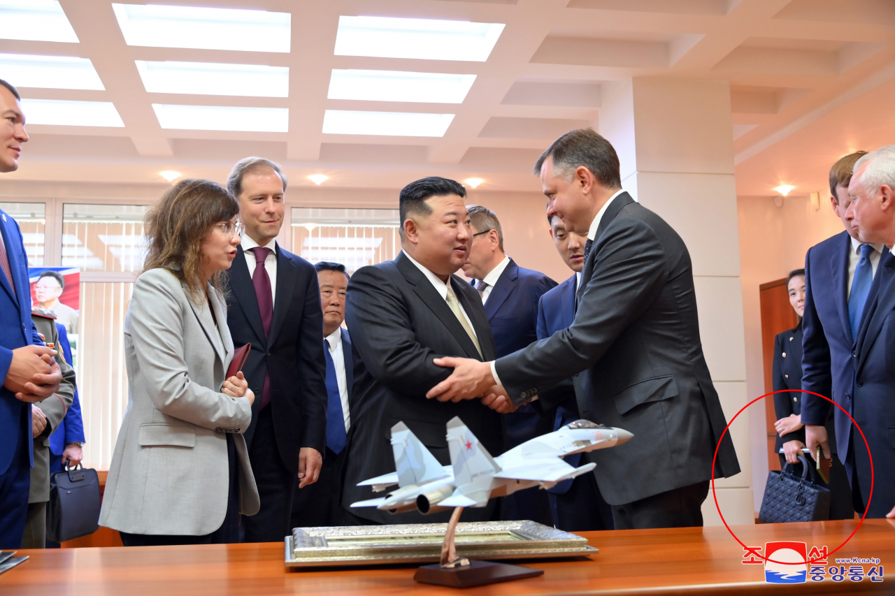 In a photograph from the North's official Korean Central News Agency, Kim Yo-jong (third from right), the sister of North Korean leader Kim Jong-un (center), can be spotted holding a $7,000 Dior luxury bag during a visit to the Yuri Gagarin Aviation Plant in Komsomolsk-on-Amur, Russia, Friday. (Yonhap)