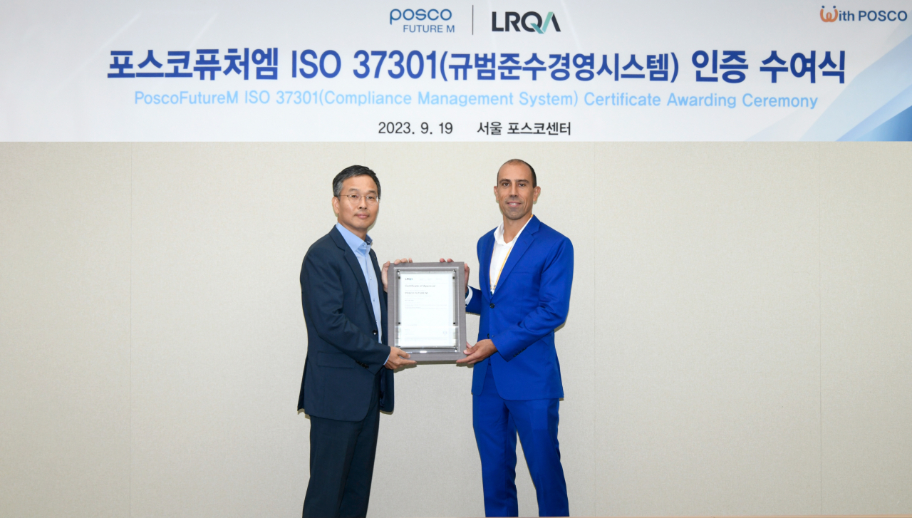 Kim Myung-ho (left), head of the legal department at Posco Future M; and Luis Cunha, APAC & MEA Certification Head at Lloyd's Register Quality Assurance, the ISO 37301 awarding body, pose for a photo with the certification plaque at a ceremony at Posco Future M's Seoul office on Tuesday. (Posco Future M)