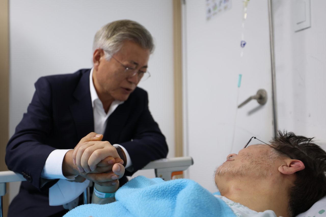 In this photo, Democratic Party of Korea Chair Rep. Lee Jae-myung (right) is seen holding the hand of former President Moon Jae-in on Tuesday as Lee had to be hospitalized in Jungnang-gu in Seoul on his hunger strike's 20th day. (Joint Press Corps)