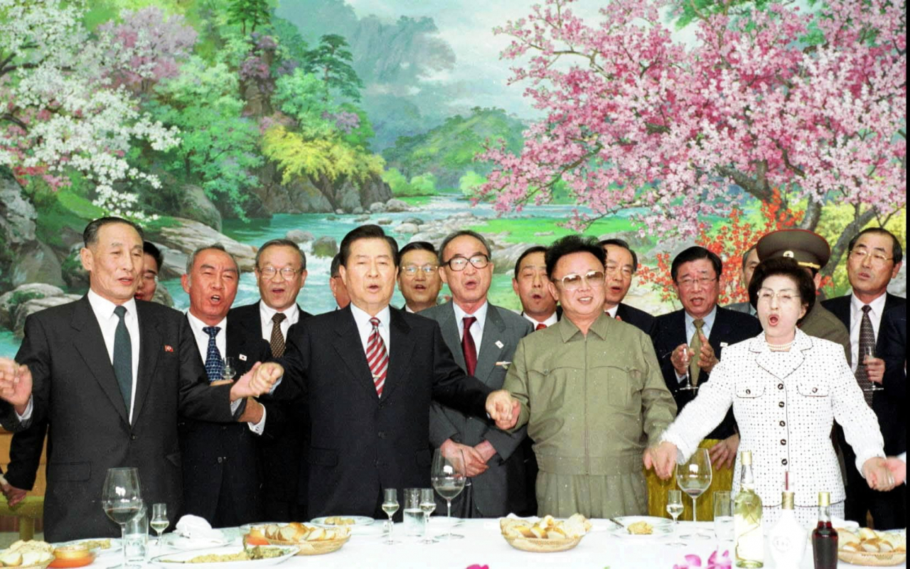 Former President Kim Dae-jung (second from left), former North Korean leader Kim Jong-il (second from right) and former South Korean first lady Lee Hee-ho (right) hold hands as they sing 