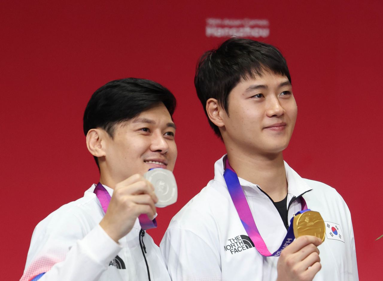 South Korean sabre fencers Oh Sang-uk (right) and Gu Bon-gil hold up their gold and silver medals from the men's individual competition at the Asian Games at Hangzhou Dianzi University Gymnasium in Hangzhou, China, on Monday. (Yonhap)
