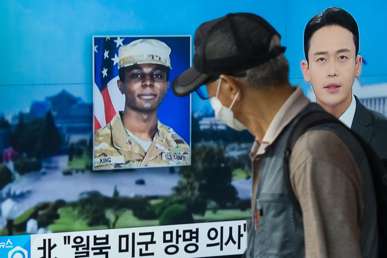 A man walks past a television showing a news broadcast featuring a photo of US soldier Travis King, who ran across the border into North Korea while part of a tour group visiting the Demilitarized Zone on South Korea's border on July 18. (AFP/Yonhap)