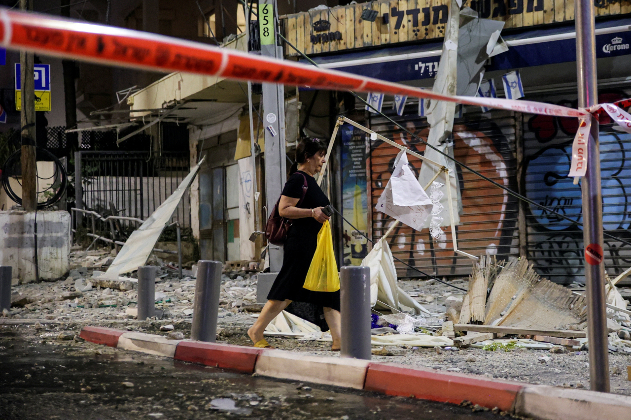 A woman walks past the site where a rocket launched from the Gaza Strip landed in Tel Aviv, Israel on Saturday (Reuters-Yonhap)