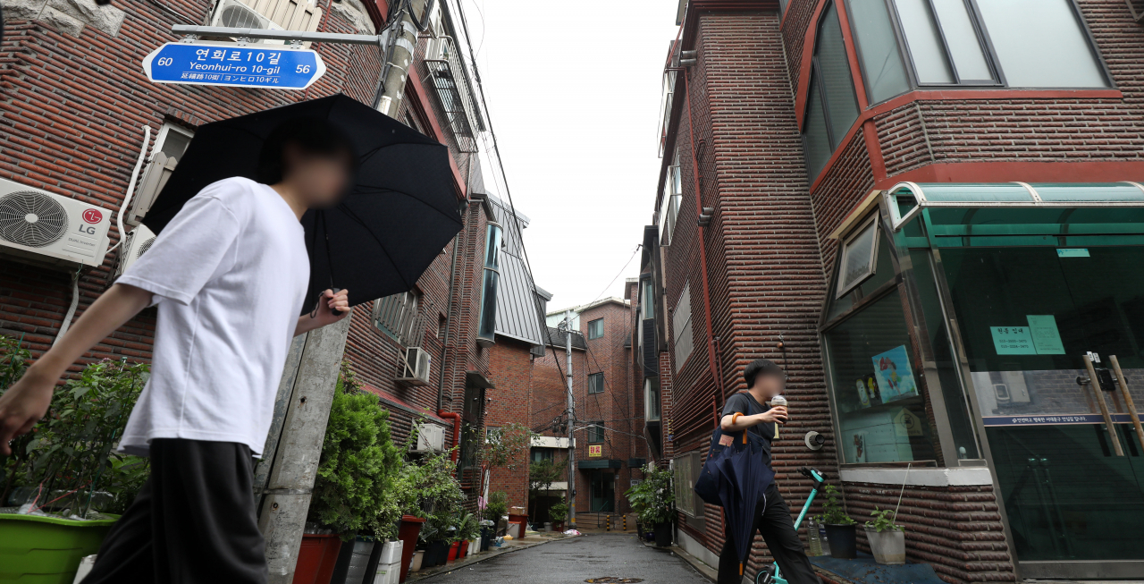 People walk on a street in a densely populated residential area near a university campus in Seoul on July 18. (Newsis)