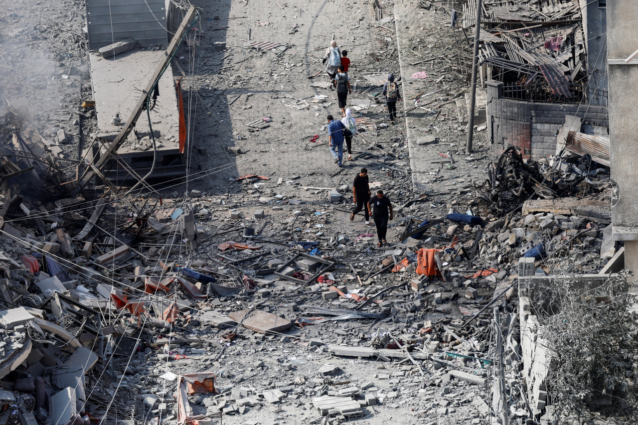 Palestinians walk through the rubble of destroyed residential buildings in the aftermath of Israeli strikes in Gaza City, October 10, 2023. (Reuters-Yonhap)