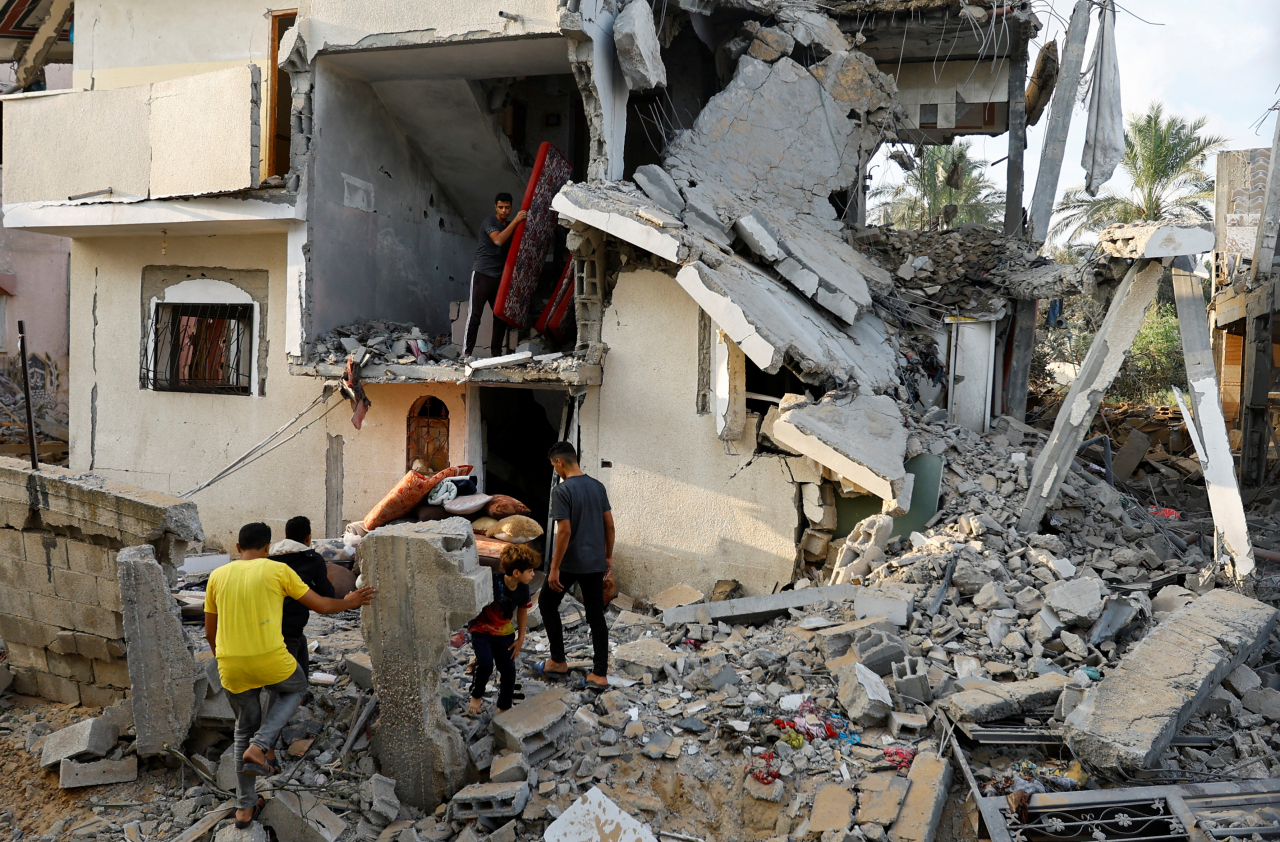 Palestinians carry out belongings from a damaged house, following Israeli strikes, in Khan Younis in the southern Gaza Strip on Wednesday. (Reuters-Yonhap)
