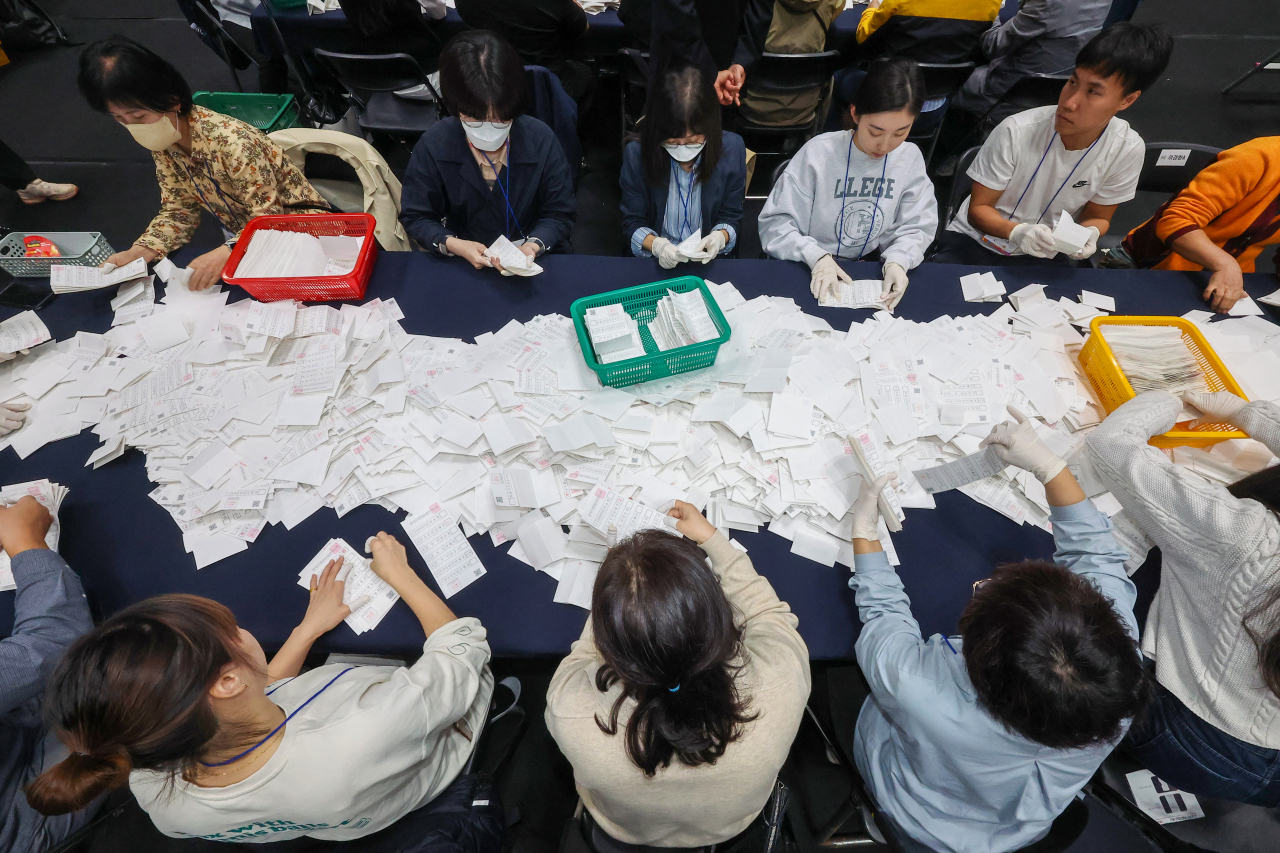 Election officials sort ballot papers to count votes for the Gangseo Ward chief by-election at a sports center in Seoul on Wednesday night. (Yonhap)