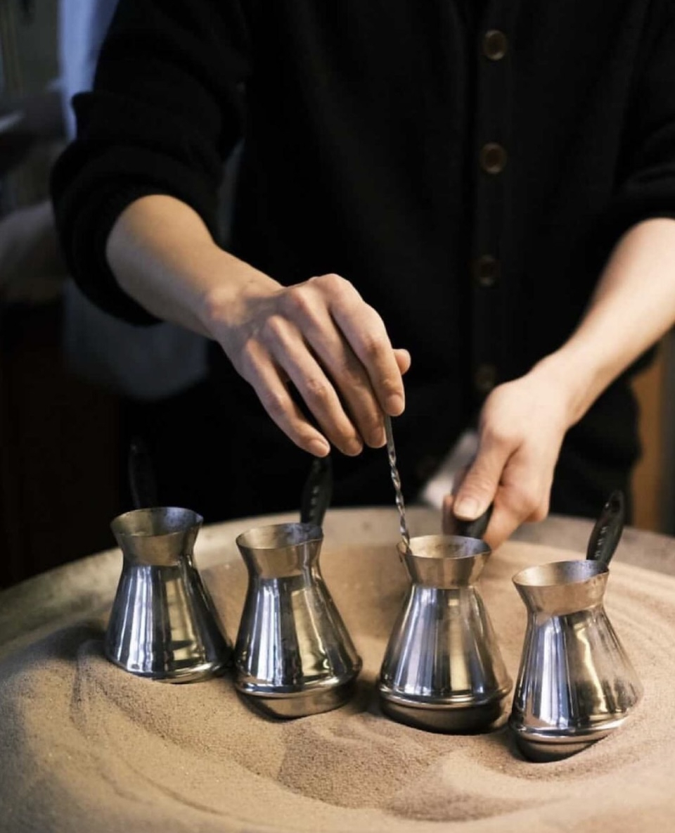 A staff brews coffee on hot sand. (Sand Coffee Nontanto)