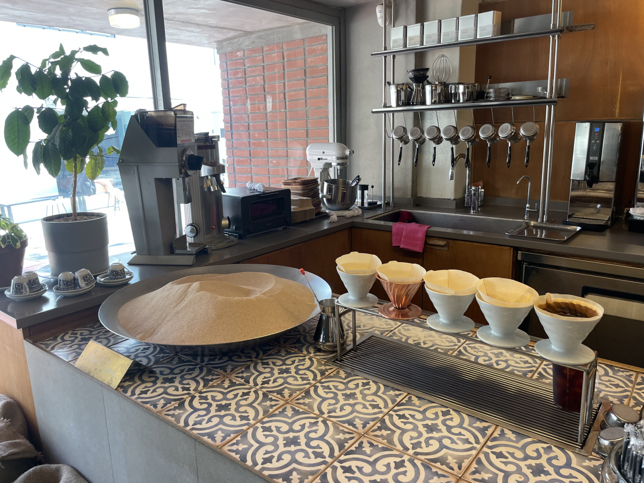 Hot sand on a pan (left) and a coffee brewing stand (right) at Nontanto Coffee. (Kim Da-sol/The Korea Herald)