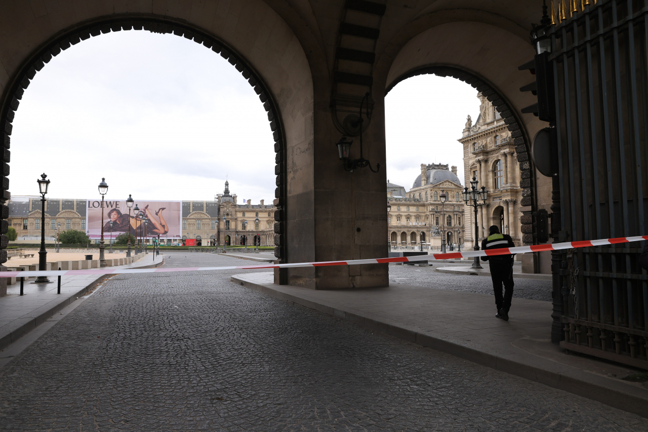 Police officers stand guard outside the Louvre Museum as people are evacuated after it received a written threat, in Paris, Saturday. The Louvre Museum says it is closing for the day and evacuating all visitors and staff after a threat. (AP-Yonhap)