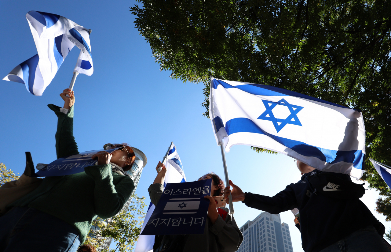 Demonstrators hold up Israel's national flag and a sign that reads 