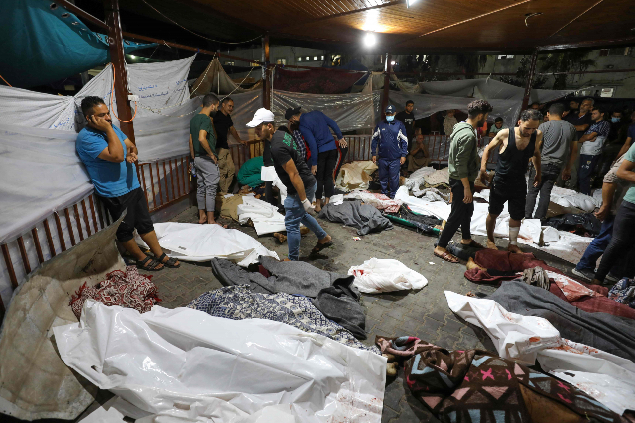 People gather around bodies of Palestinians killed in Israeli airstrikes on the Ahli Arab hospital in central Gaza after they were transported to Al-Shifa hopsital on Tuesday (AFP-Yonhap)