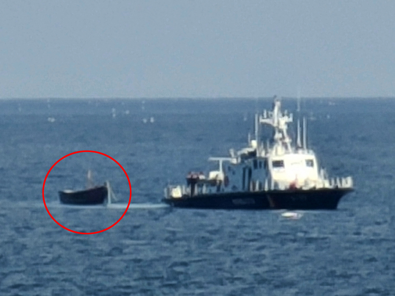 A wooden boat (in red circle) is towed by a South Korean military vessel toward a port in Yangyang, Gangwon Province, northeastern South Korea, on Tuesday, after a group of four unidentified individuals from North Korea crossed the eastern maritime inter-Korean border on the boat and spotted in waters off the nearby city of Sokcho. (Yonhap)