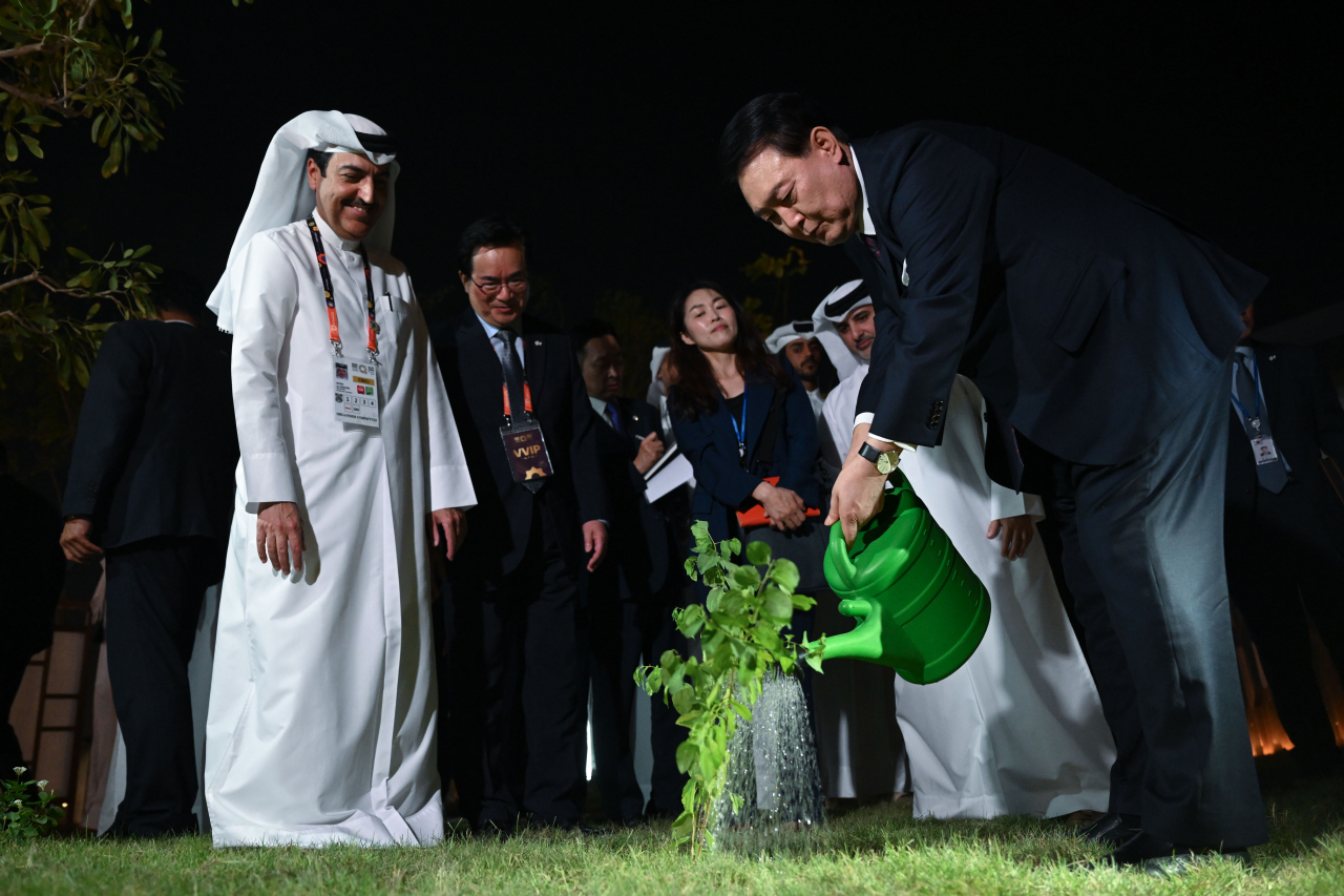 South Korean President Yoon Suk Yeol (right) waters a tree given as a gift by Qatari Emir Sheikh Tamim bin Hamad Al Thani at the South Korean pavilion of the 2023 International Horticultural Exposition in Doha on Tuesday. (Yonhap)