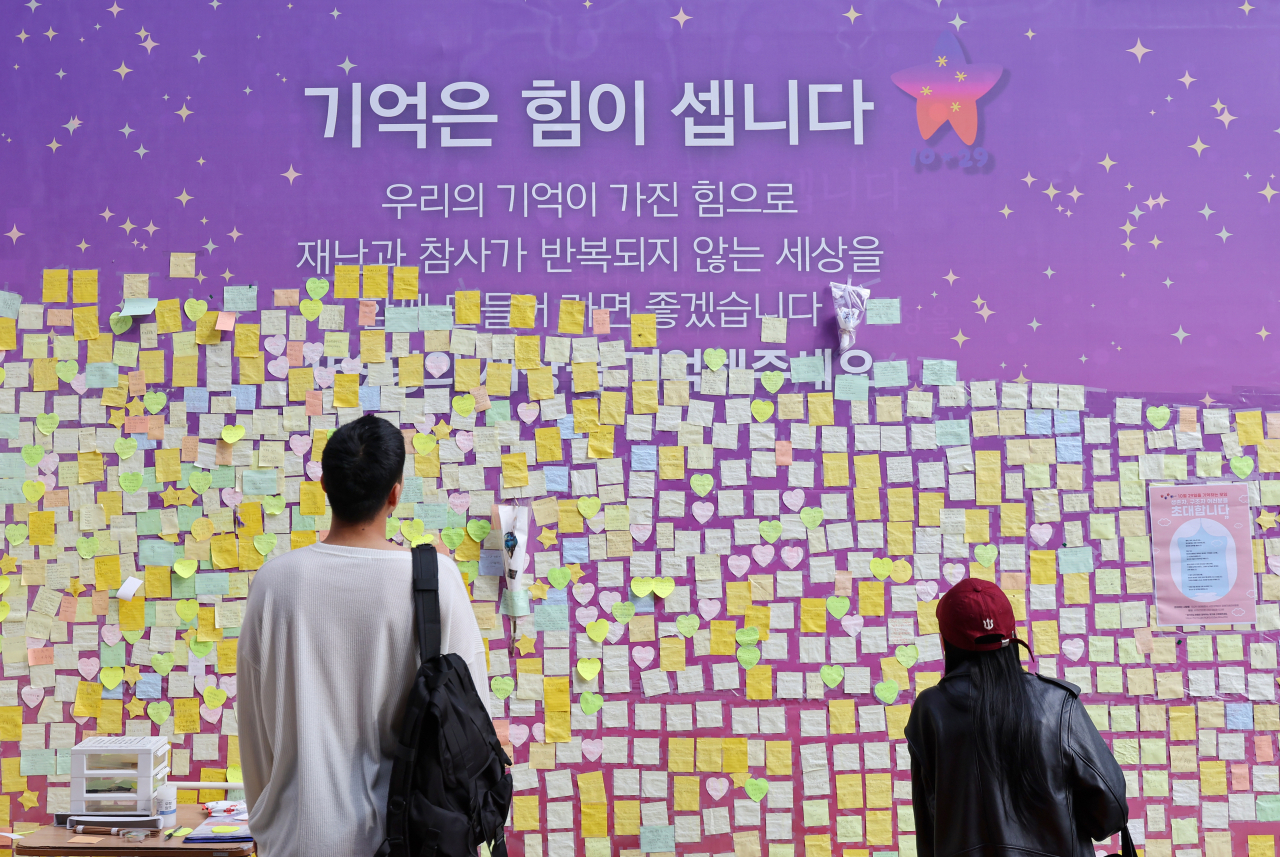 Passersby gaze at messages attached to a board set up to remember victims of the Itaewon crowd crush on Sunday, a week before the first anniversary of the tragedy that occurred in a narrow alley in central Seoul on Oct. 29 last year. (Yonhap)