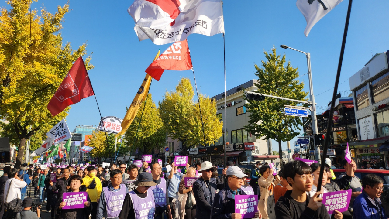 Participants march from Itaewon Station to Seoul Plaza, the venue for the main memorial service, waving flags of participating civic groups, labor unions, and political parties. (Lee Jung-youn/The Korea Herald)