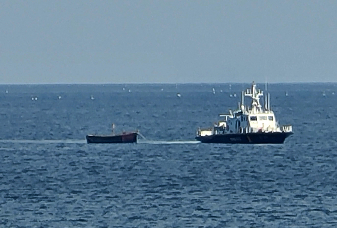 A wooden boat is towed by a South Korean military vessel toward a port in Yangyang, Gangwon Province, northeastern South Korea, on Tuesday, after a group of four unidentified individuals from North Korea crossed the eastern maritime inter-Korean border on the boat and were spotted in waters off the nearby city of Sokcho. (Yonhap)