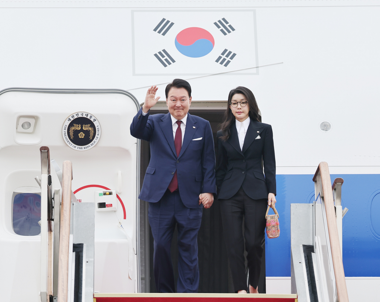 President Yoon Suk Yeol (left), alongside his wife, Kim Keon Hee, disembarks from the presidential plane at Seoul Air Base in Seongnam, south of Seoul, on Thursday, after finishing a two-nation state visit that took him to Saudi Arabia and Qatar. (Yonhap)