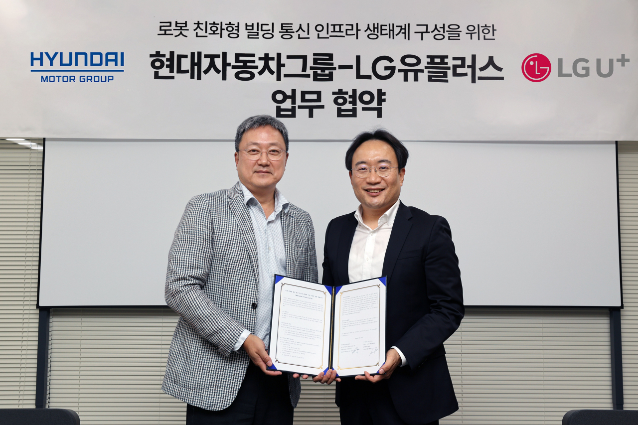 Officials from Hyundai Motor Group and LG Uplus hold up their partnership agreement on co-developing communication infrastructure for robot-friendly buildings in Seoul on Wednesday. (LG Uplus)