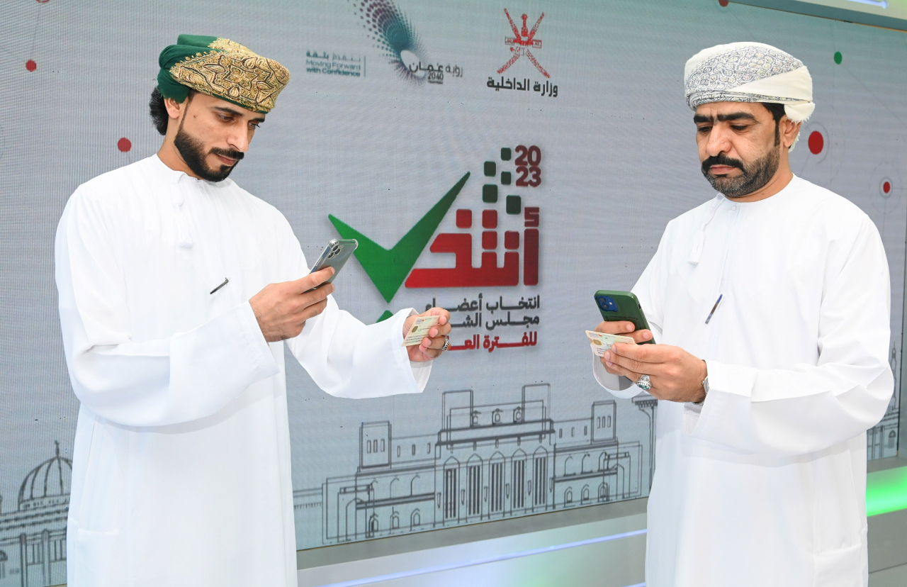 Omani citizens take photos of their ID cards as part of a verification process to make sure ID cardholders are registered voters and ready to vote via mobile app. (Courtesy of Oman News Agency)