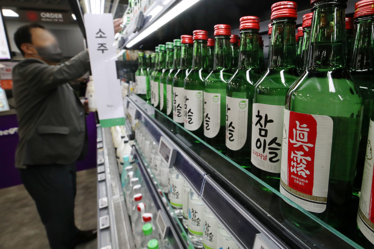 A shopper chooses a bottle of soju at a hypermarket in Seoul on Tuesday. (Newsis)