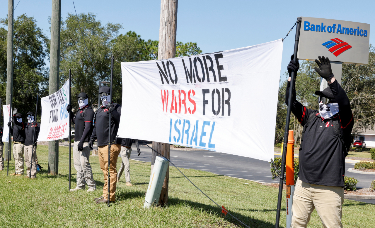 Members of the white nationalist group NatSoc Florida wave to motorists as they hold banners in response to the war between Israel and Hamas during a protest in Lady Lake, Florida, Oct. 21. (Reuters-Yonhap)