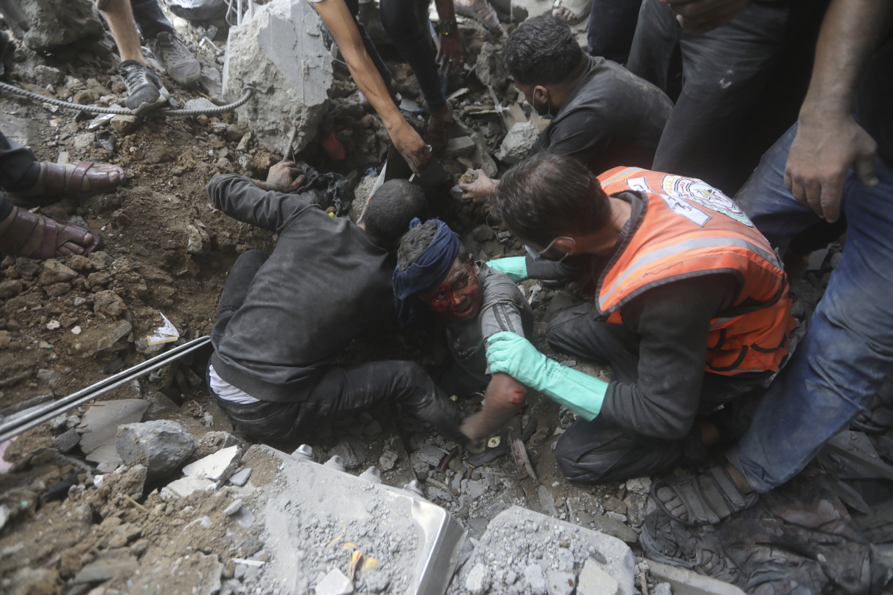 Palestinian rescuers try to pull an injured boy out of the rubble of a destroyed building following an Israeli airstrike in Bureij refugee camp, Gaza Strip, Thursday. (AP- Yonhap)