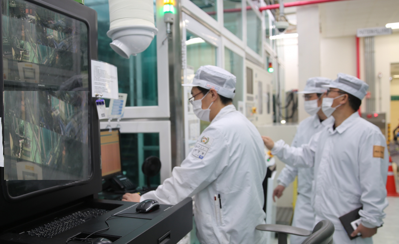 Samsung Electro-Mechanics employees handle equipment for chip package substrates at the manufacturing site in Sejong. (Samsung Electro-Mechanics)