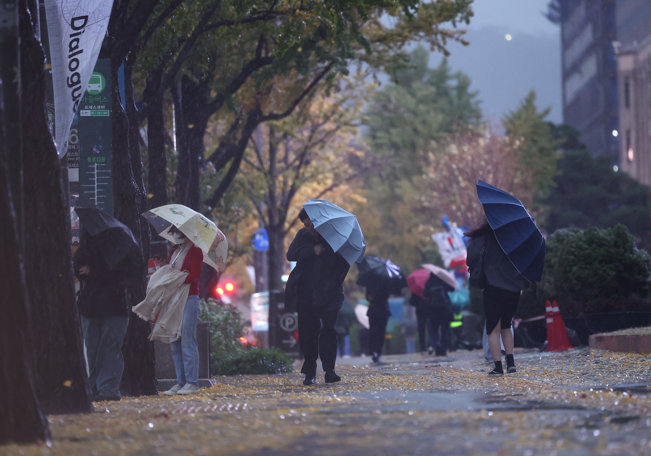 Passersby walk near Seoul City Hall, Jung-gu, Seoul, holding umbrellas on Monday morning, when strong wind and rain hit the city. (Yonhap)