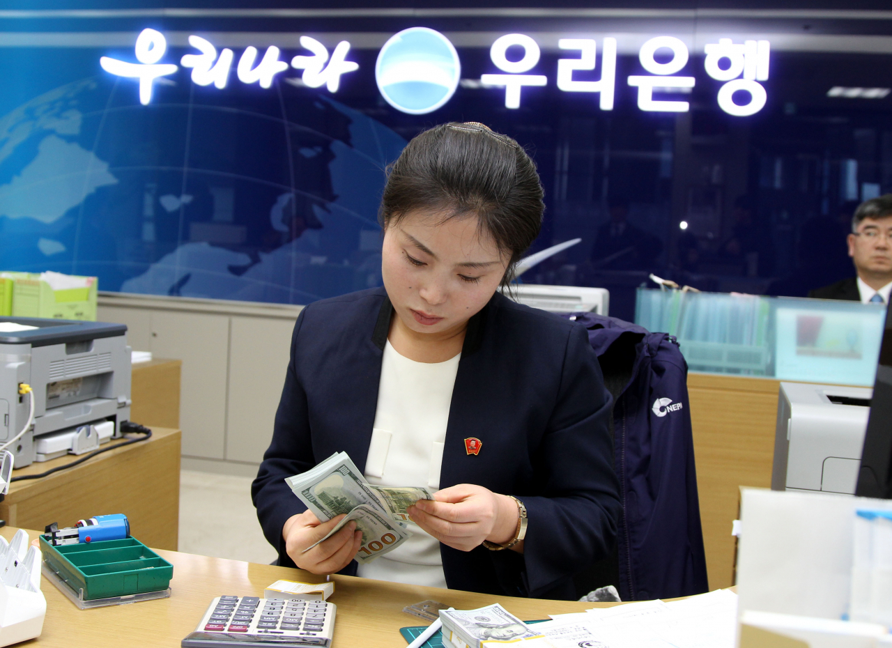 A North Korean employee conducts banking services at Woori Bank's Kaesong Industrial Complex branch in North Korea in 2013. (Newsis)