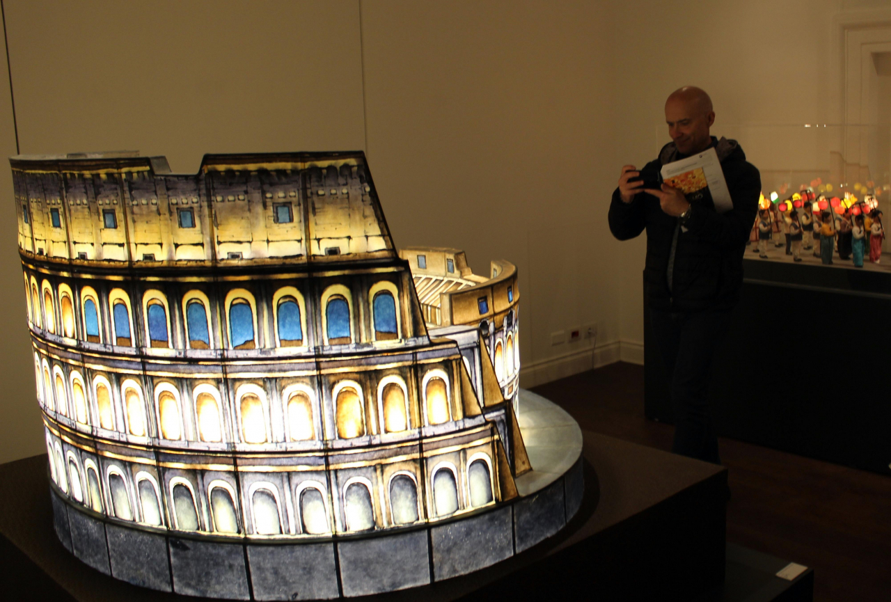 A visitor takes a photo of a lantern made to resemble Rome's Colosseum at the exhibition, 