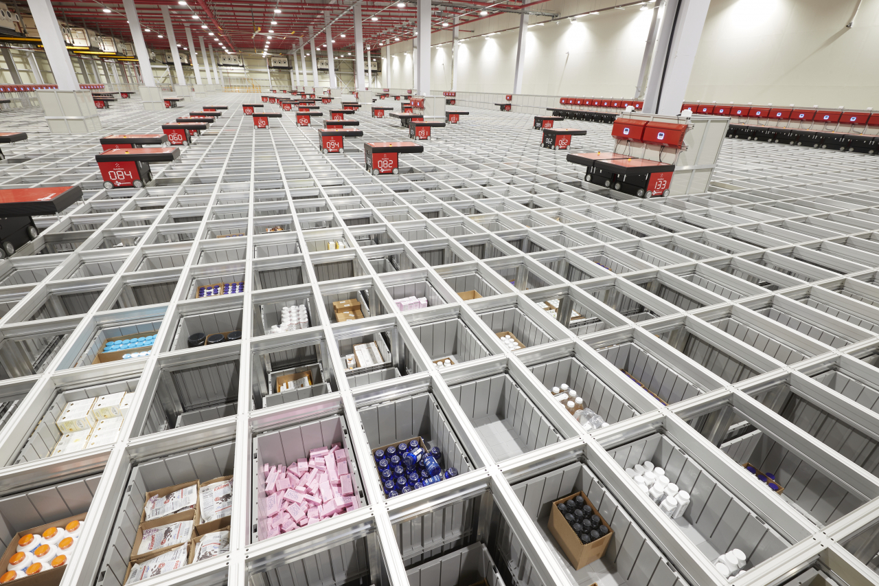 Robots move above rows of bins to transfer them to the packaging station at CJ Logistics' Global Distribution Center in Incheon on Thursday. (CJ Logistics)