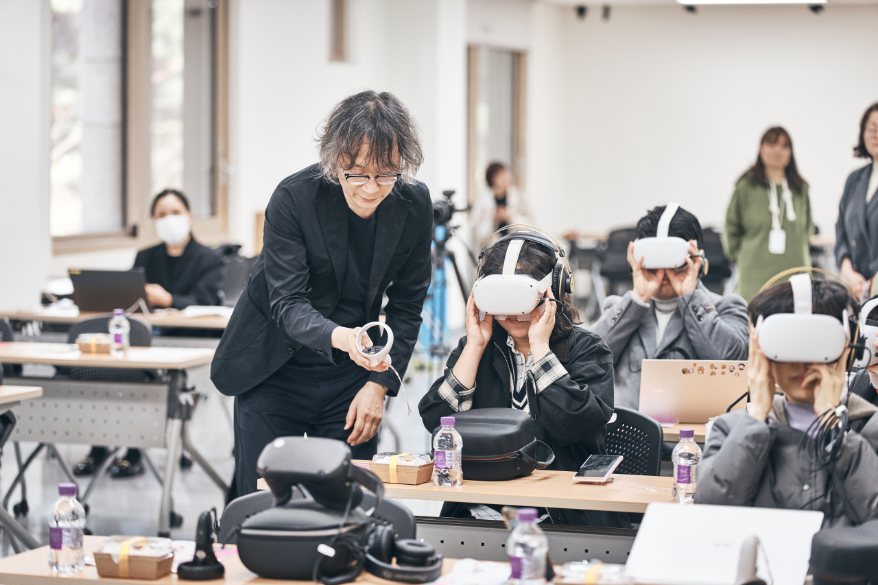 Director Seo Hyun-suk helps a participant during a virtual reality demonstration for “The Origin of Orchestra.” (National Theater of Korea)