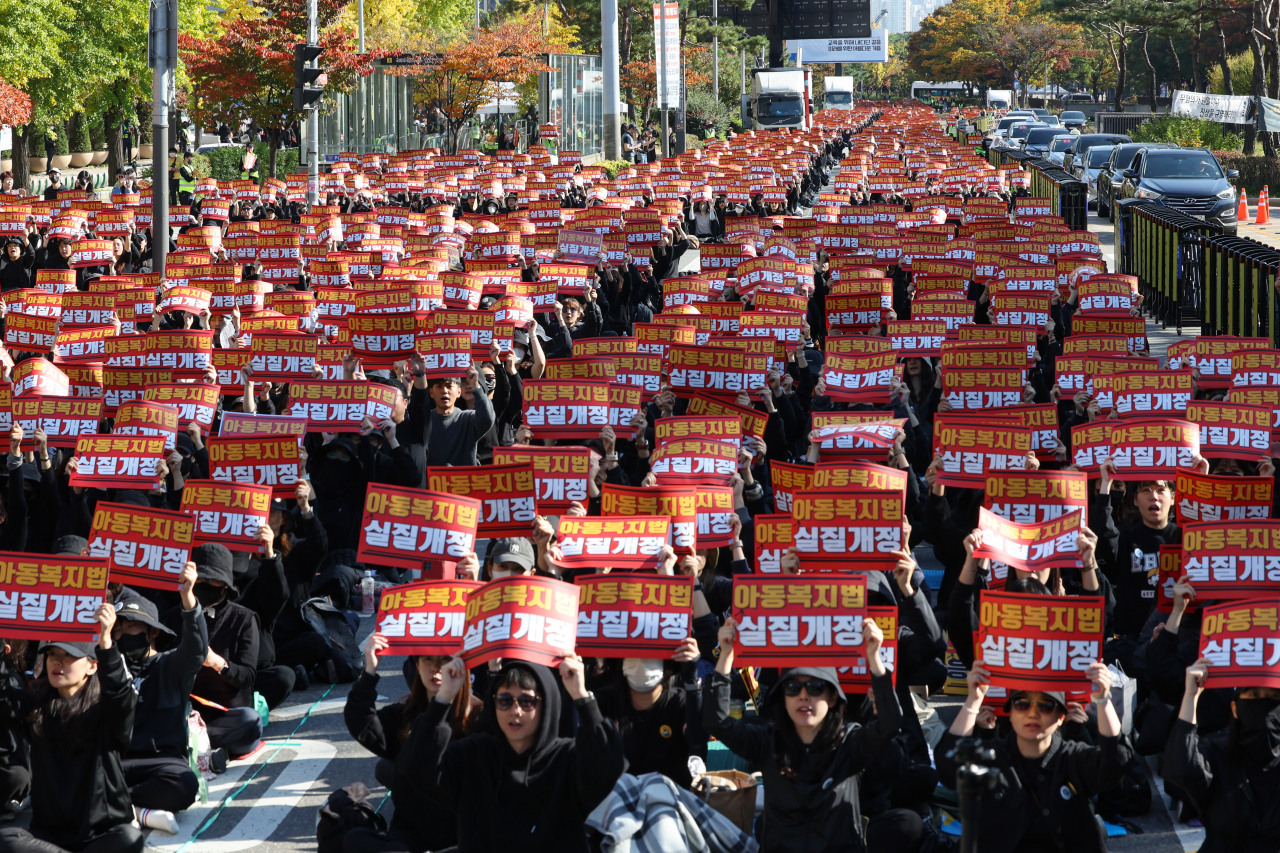 Protesters in black chant slogans on Oct. 28 in Yeouido, Seoul, holding signs calling for the revision of the Child Welfare Act, which they argue leads to excessive complaints from parents claiming 