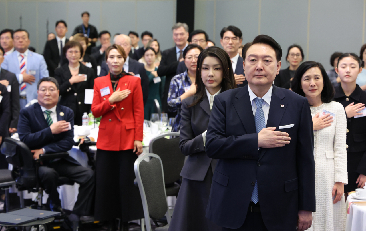President Yoon Suk Yeol (front) and participants in the lunch meeting with overseas Koreans and Korean descent in San Francisco salute South Korea's national flag on Wednesday local time. (Yonhap)