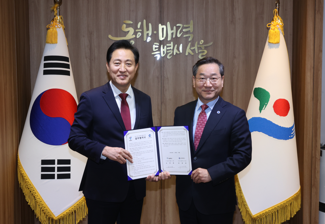 Seoul Mayor Oh Se-hoon (left) and Incheon Mayor Yoo Jeong-bok (right) pose for a picture at Seoul City Hall after signing the new public transportation policy agreement, Friday. (Yonhap)