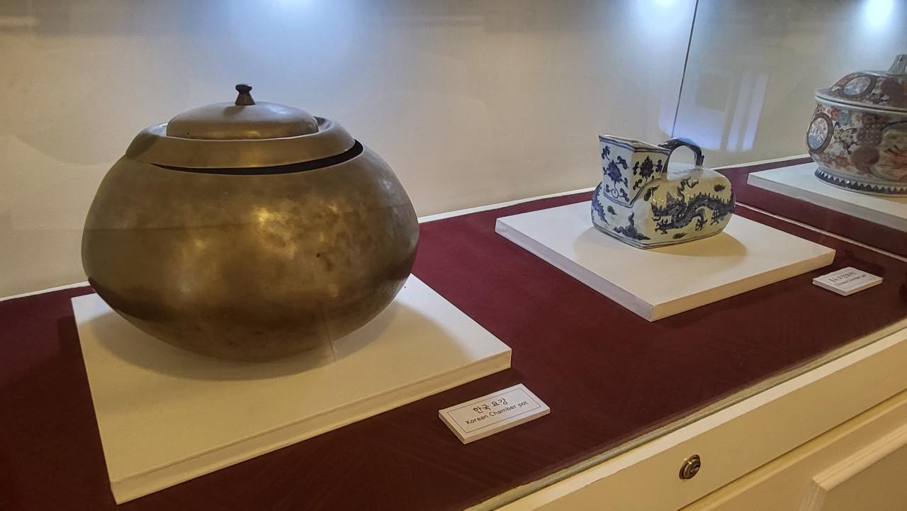 Old chamber pots from Korea (left) and China, are on display at Haewoojae. (Kim Hae-yeon/ The Korea Herald)