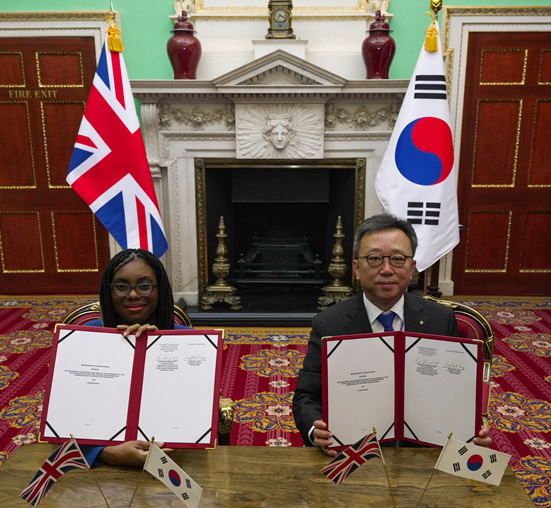 Shinhan Bank CEO Jung Sang-hyuk (right) and British Business and Trade Secretary Kemi Badenoch pose for a photo after signing an investment agreement at Mansion House in London, Tuesday. (Shinhan Bank)