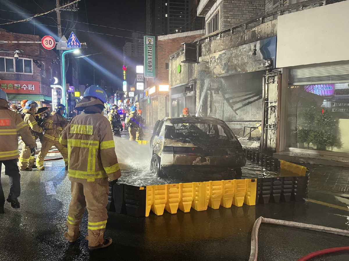 Firefighters immersed the burning taxi in a mobile pool to extinguish the fire in Busan, Wednesday. (Busan Metropolitan City Fire Disaster Headquarters)