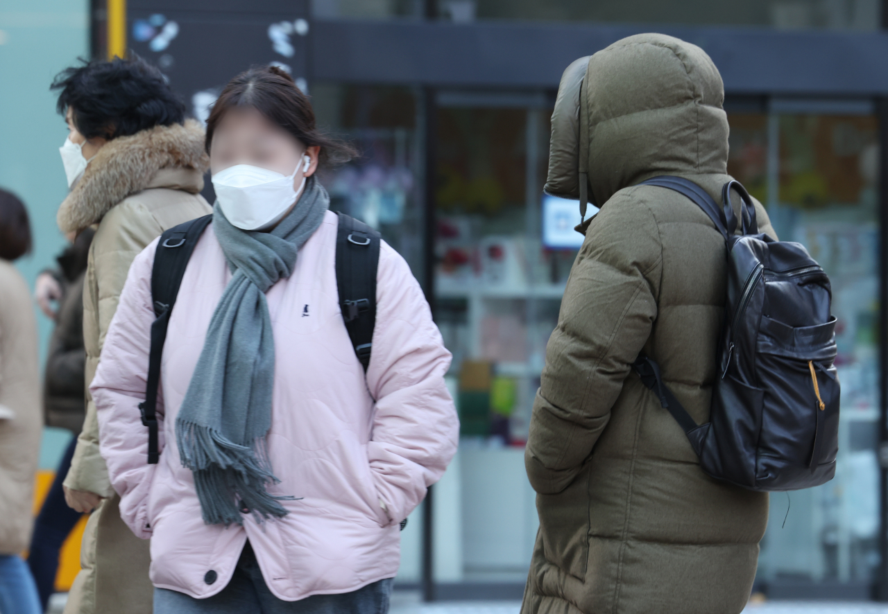 Passersby walk through Myeong-dong, Jung-gu, Seoul, on Friday morning, when the temperature sharply dropped below zero. (Yonhap)