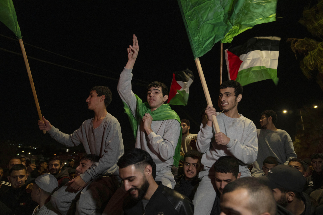 Former Palestinian prisoners who were released by the Israeli authorities, fly Palestinian and Hamas flags while they are carried on the shoulders upon their arrival in the West Bank town of Beitunia, Friday, Nov. 24, 2023. (AP-Yonhap)