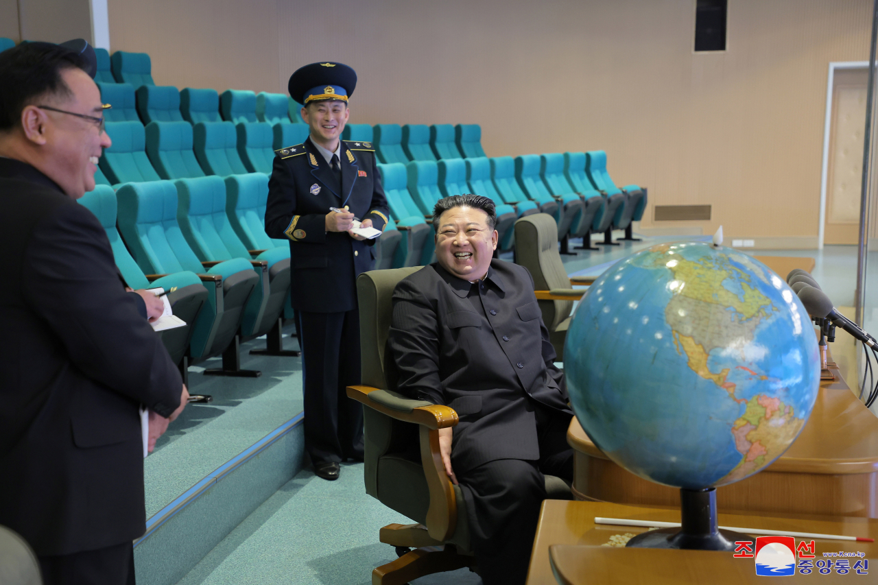 This photo, carried by North Korea's official Korean Central News Agency on Nov. 25, 2023, shows the North's leader Kim Jong-un speaking with officials, as he visited the National Aerospace Technology Administration the previous day to examine photos taken by the country's new military spy satellite. (Yonhap)